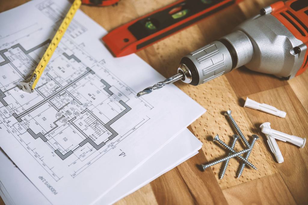 Architectural floor plan on a desk with a tape measure and drawing tools